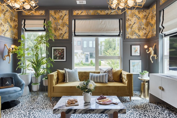 Ein gemütliches Wohnzimmer mit einer Couch, einem Couchtisch mit Snacks und einem großen Fenster mit Blick ins Freie.