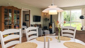 A dining area with a round table, white chairs, and woven placemats. - 8 Person Holiday Home in Stege (Stege)