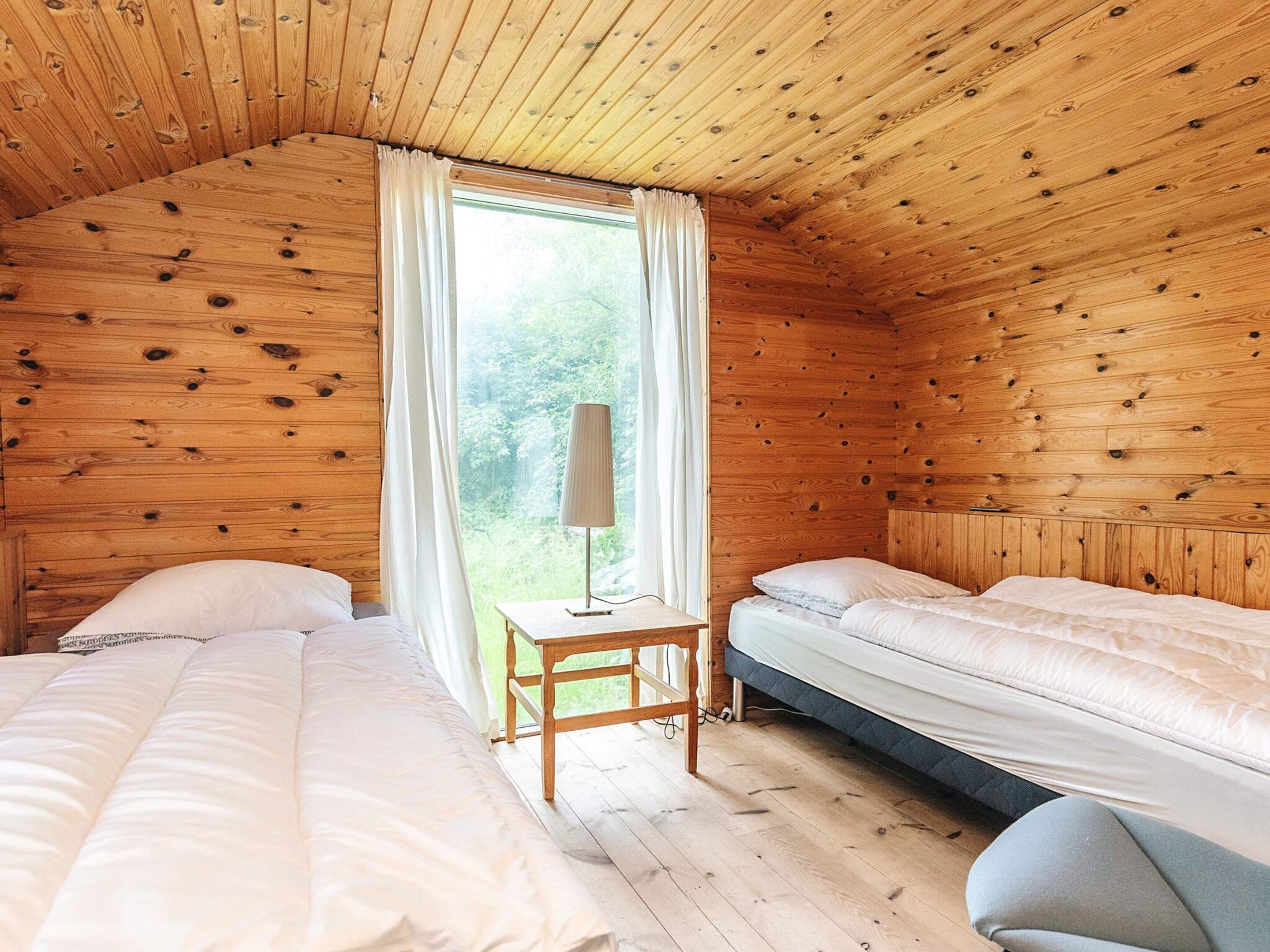 A cabin with two beds, a small table, and a window with curtains.