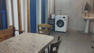 A kitchen with a table, chairs, a washing machine, and a sink.