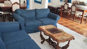 A living room with a blue sofa set, a wooden coffee table, and a dining area with a table and chairs. - Historical House in Alsancak (Konak)