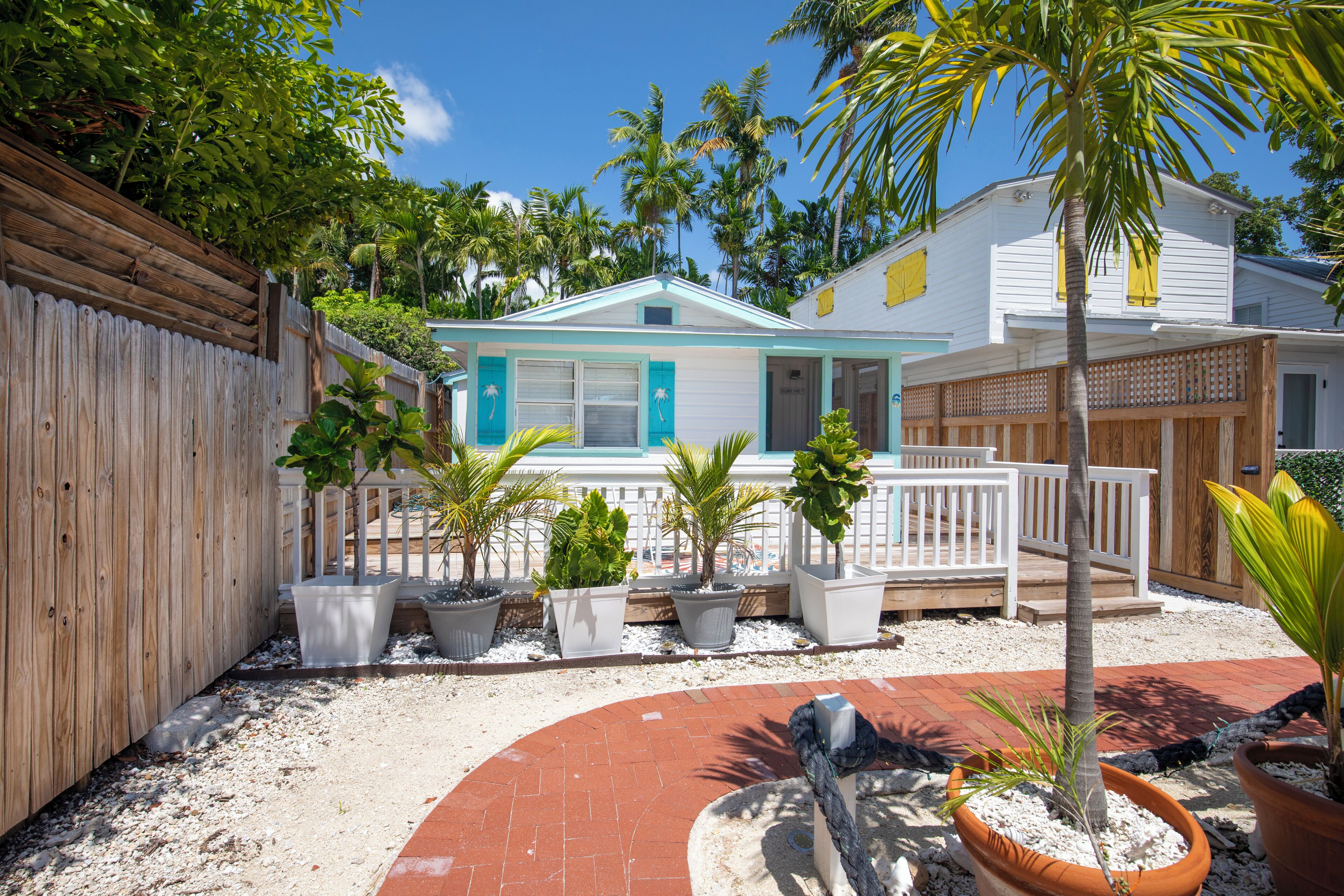 A house with a white exterior, a wooden fence, and potted plants.