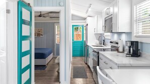 A compact kitchen with white cabinets, a coffee maker, and a microwave. - Shared Pool + Backyard Lounge | Charming Cottage | Steps to Waterfront Dining (Key West)