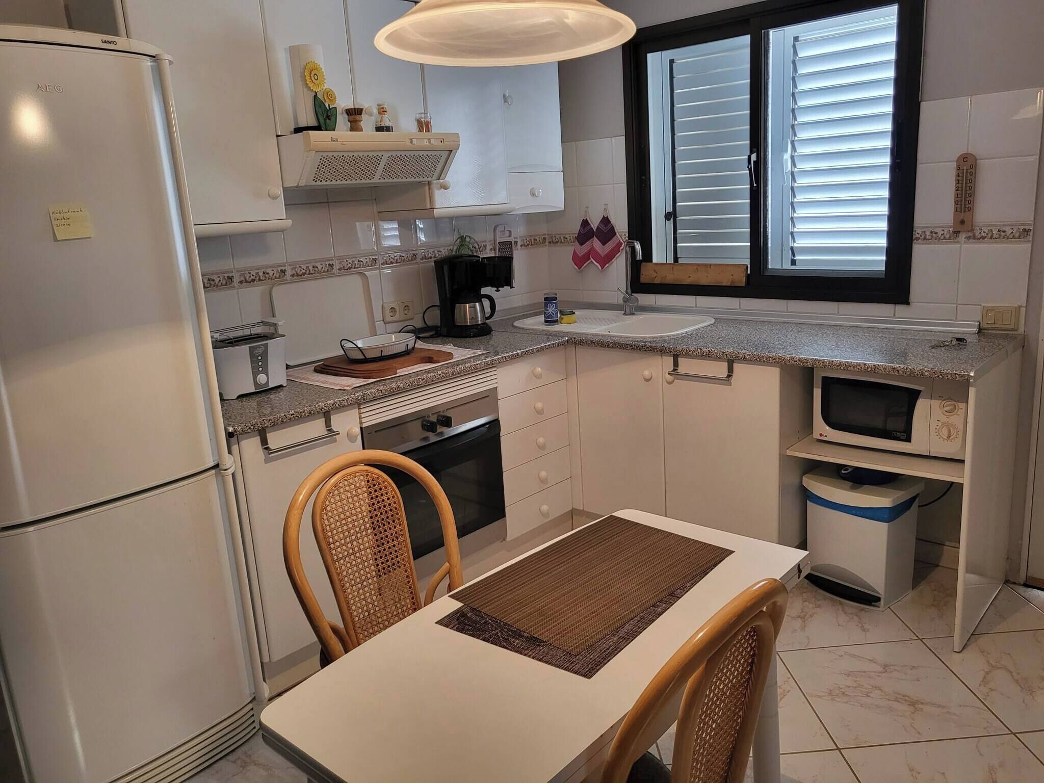 A compact kitchen with a refrigerator, stove, microwave, sink, and a dining area with chairs and a table.