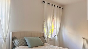 Une chambre à coucher avec un lit, des rideaux, une fenêtre et un luminaire au plafond.