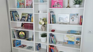 Une bibliothèque blanche contenant divers livres et objets décoratifs.
