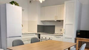 Une cuisine moderne avec des meubles blancs, une table à manger en bois et des chaises grises.