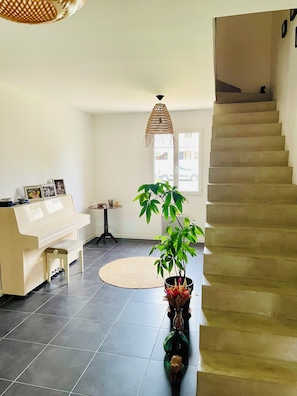 A living room with a piano, a staircase, a potted plant, and a woven light fixture. - Pool villa near Cassis 8/9 sleeps Roquefort-La-Bédoule (Roquefort-la-Bédoule)