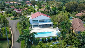 A modern two-story house with a swimming pool, surrounded by lush greenery and palm trees. - 5BR Hispaniola Villa in Sosua (Sosúa)