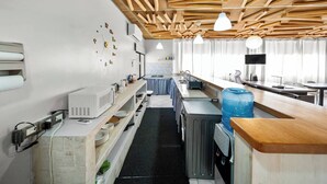 A kitchen with wooden ceiling beams, a microwave, a water dispenser, and a sink. - Centric Studio in Sosua Center Pool & Workspace (Sosúa)