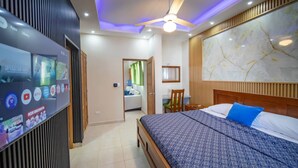 A hotel room with a bed, a ceiling fan, a TV mounted on the wall, and a marble wall. - Casa de Compai Unit 8  AC, WiFi & Full Kitchen (Sosúa)