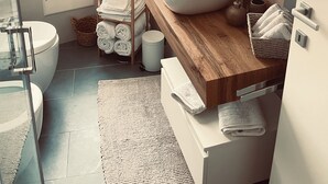 Ein modernes Badezimmer mit einem großen Waschbecken, einem Spiegel, einer Toilette und einer Dusche.