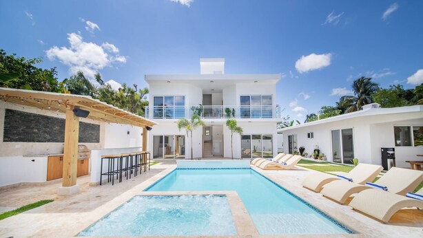 A modern two-story house with a swimming pool, outdoor bar, and lounge chairs. - 14 BR Getaway 2 mins from Sosua action! (Sosúa)