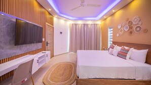 A modern bedroom with a flat-screen TV, a wooden desk, a bed with white bedding, and a ceiling fan. - 14 BR Getaway 2 mins from Sosua action! (Sosúa)