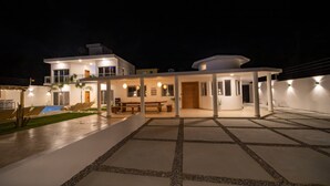 A modern two-story house with a covered patio, outdoor seating, and a swimming pool. - 14 BR Getaway 2 mins from Sosua action! (Sosúa)