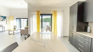 Eine moderne Küche mit Marmorarbeitsplatte, dunklen Schränken und einem großen Fenster mit gelben Vorhängen.