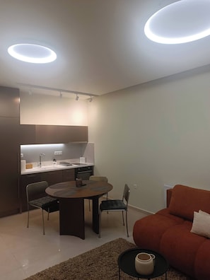 A modern kitchen with a dining area, a sofa, and a coffee table. - Cozy Apartment in Nea Ionia Greece with Modern Amenities (Nea Ionia)