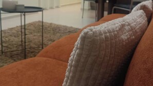 A living room with a sofa, a coffee table, and a TV mounted on the wall. - Cozy Apartment in Nea Ionia Greece with Modern Amenities (Nea Ionia)