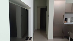 A modern kitchen with a built-in oven, a microwave, and a coffee machine. There is a small seating area with a chair and a table. - Cozy Apartment in Nea Ionia Greece with Modern Amenities (Nea Ionia)