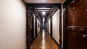 En lång, smal hall med trädörrar på båda sidor och ett mönstrat golv.
