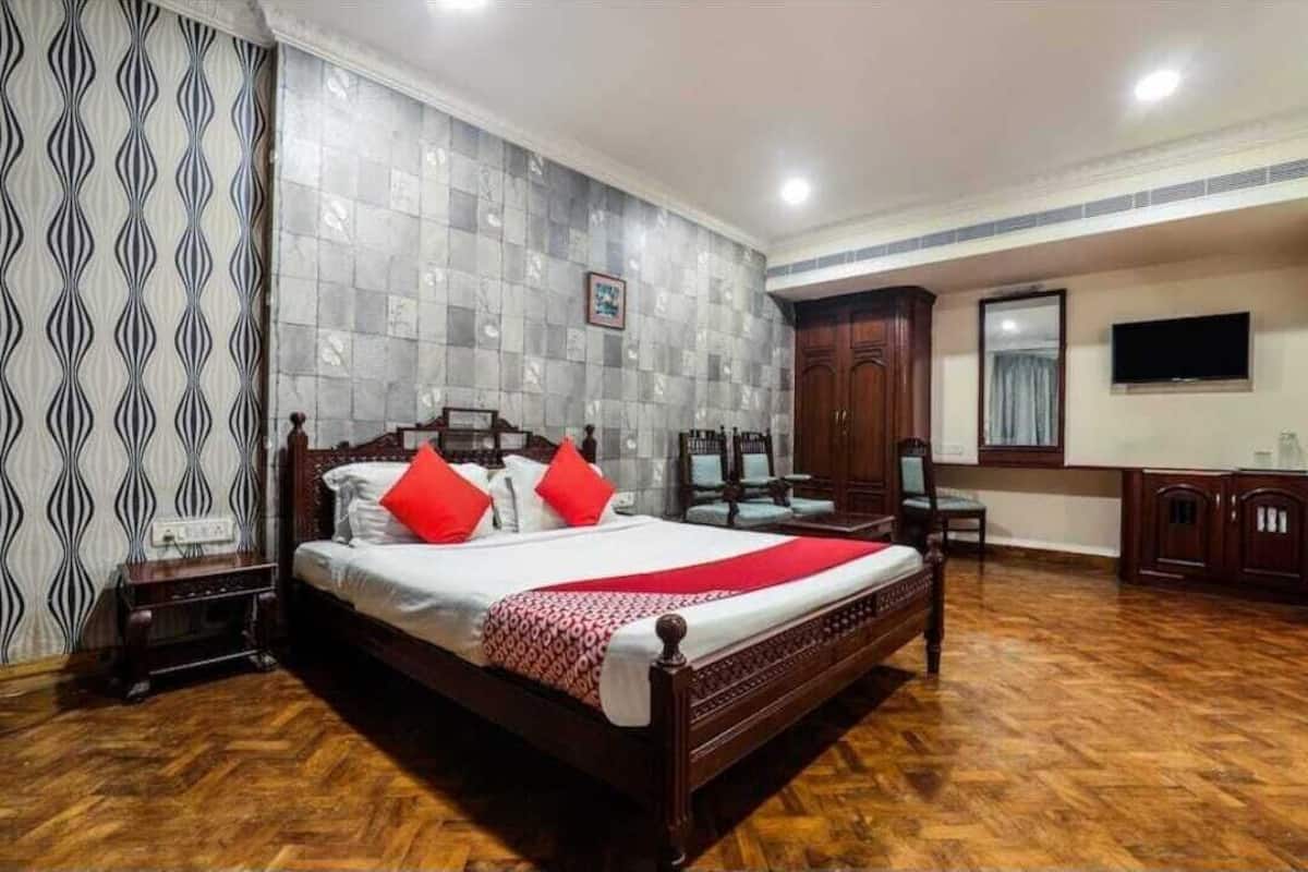 Habitació d'hotel amb un llit de fusta, televisió, escriptori i armari.