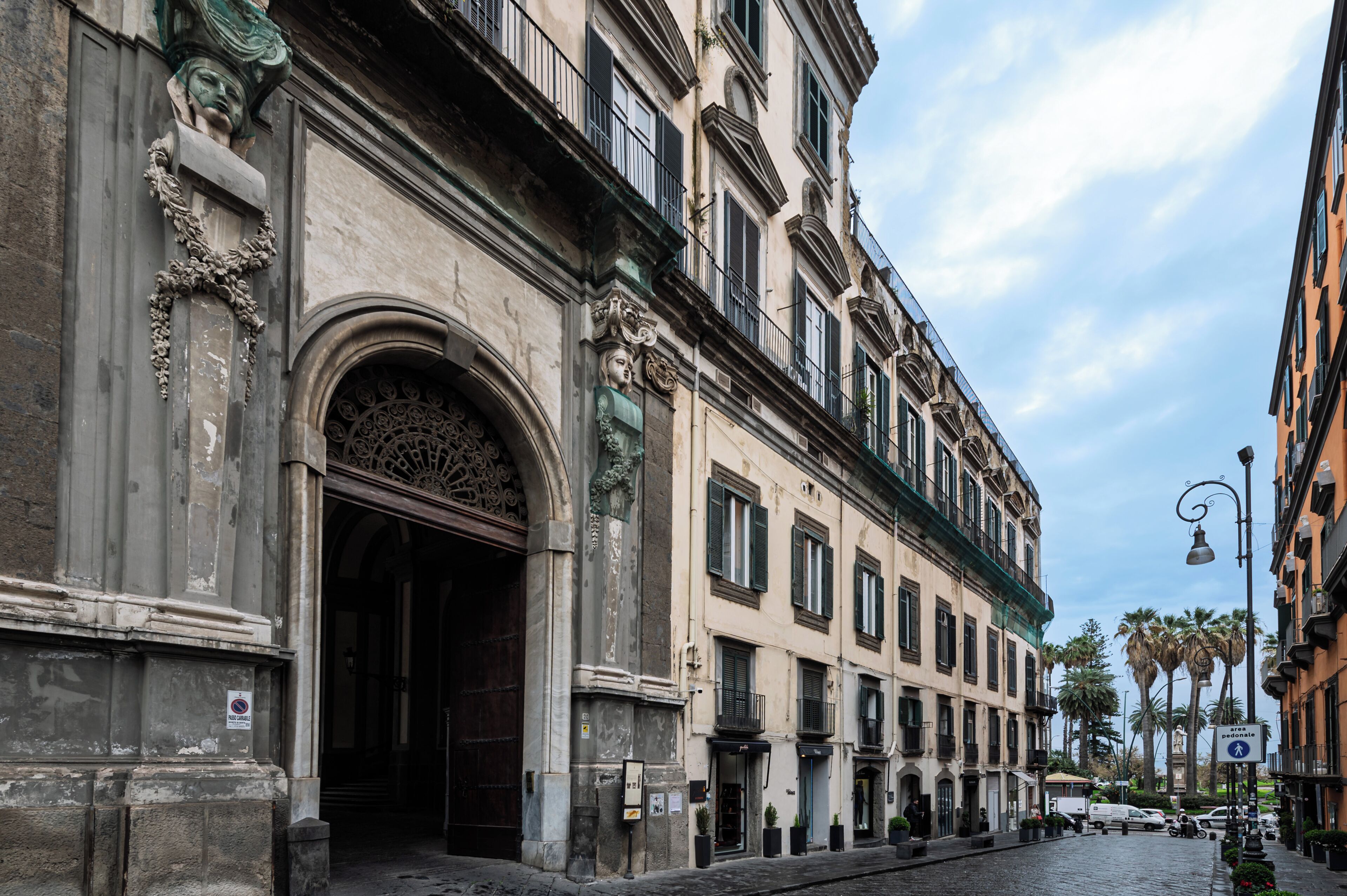 Un edificio storico con dettagli architettonici elaborati, tra cui un'ampia entrata ad arco e modanature decorative.