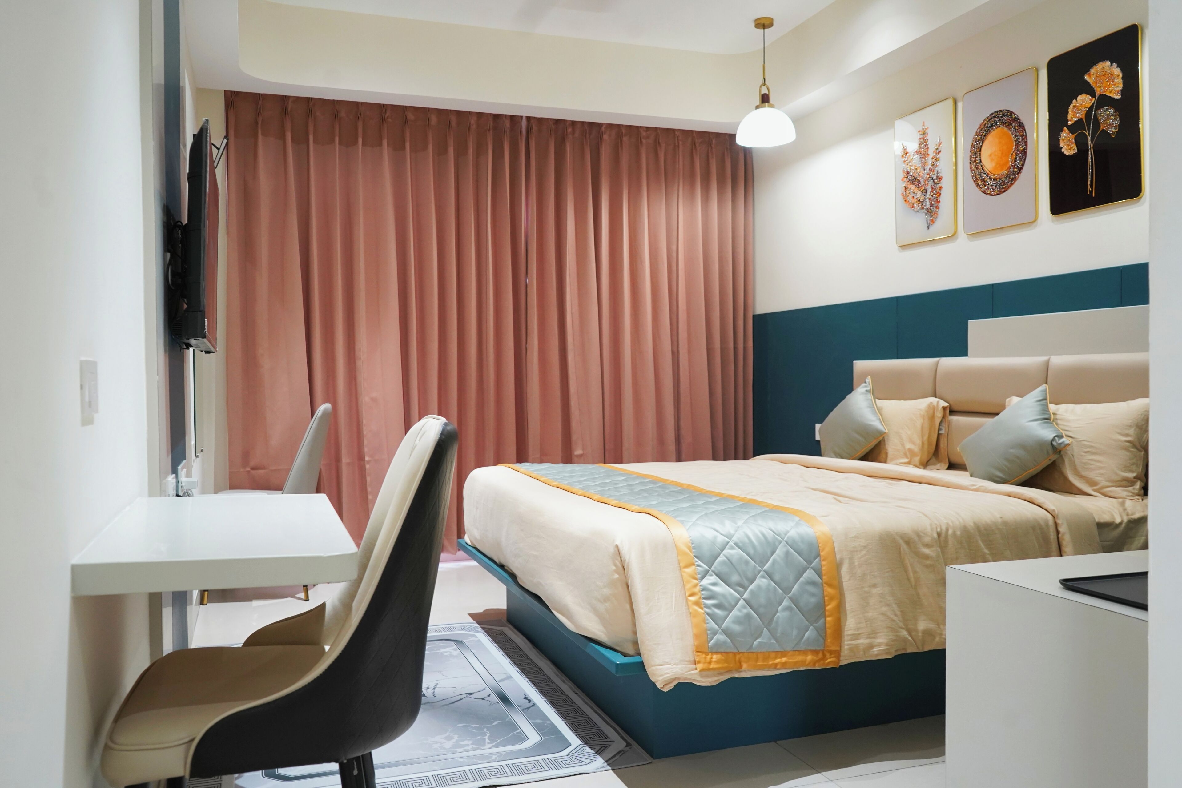 A hotel room with a bed, a desk, a chair, a television, and artwork on the wall.