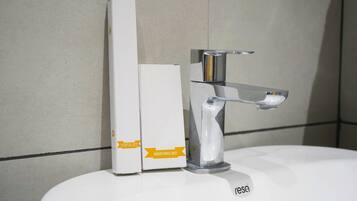 A bathroom sink with a chrome faucet and two white boxes labeled 'Dental Kit' and 'Shaving Kit' on the counter.