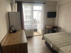 A hotel room with a bed, a desk, a television, and a window with curtains.