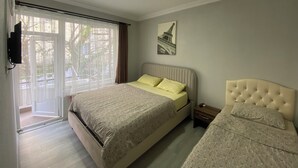 A bedroom with a bed, a nightstand, a wall-mounted TV, a window with curtains, and a picture of the Eiffel Tower. - Sinop kuzey pansiyon (Sinop)