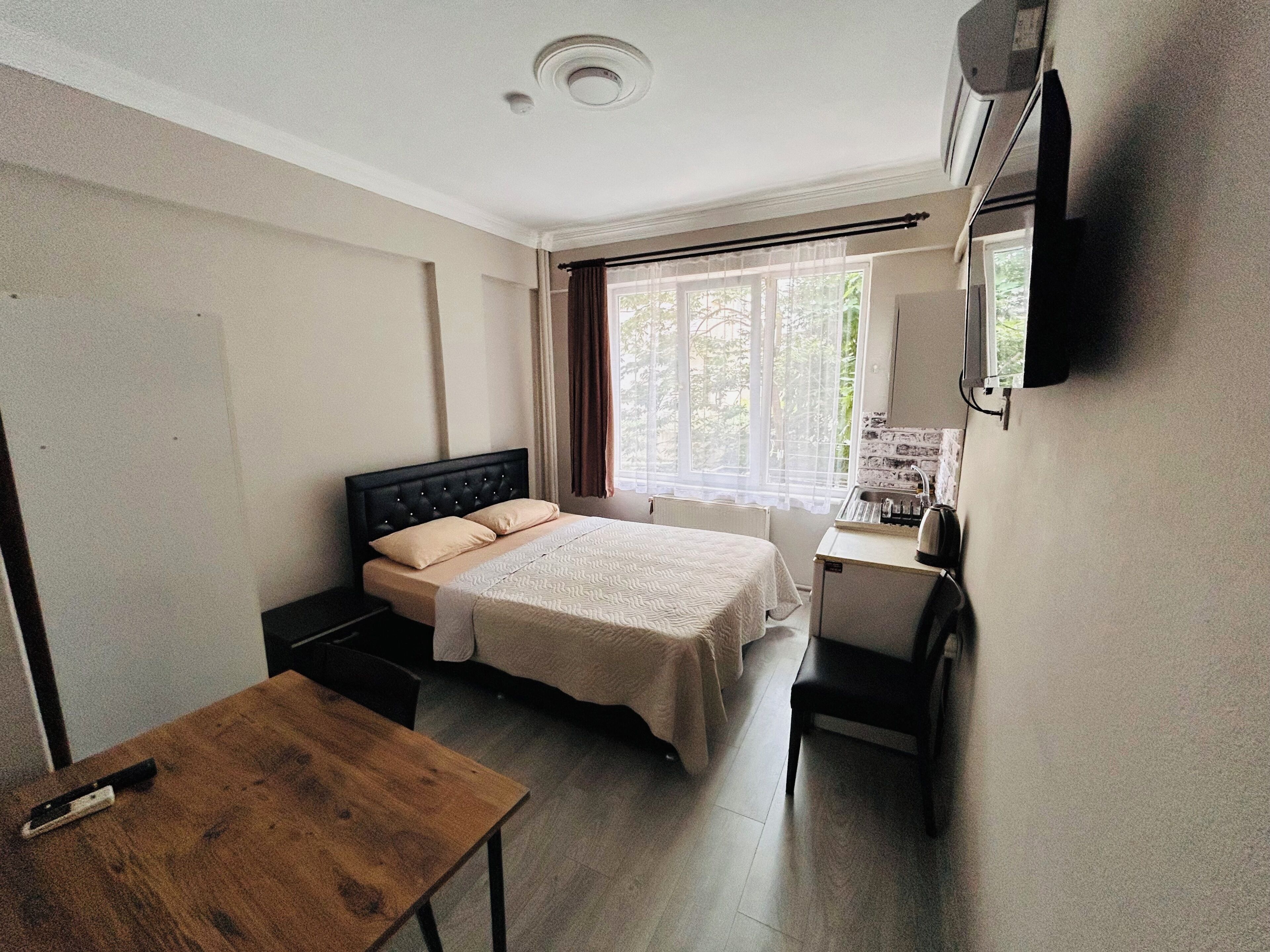 A bedroom with a bed, bedside table, and a small desk with a chair.