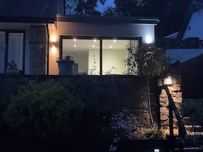 A modern house with a large glass window, a stone wall, and a potted plant.