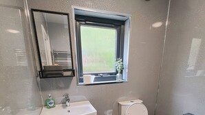 Un baño moderno con lavamanos, inodoro y ventana.