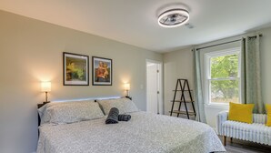 A bedroom with a bed, two wall-mounted lamps, a ladder, a window with curtains, and a radiator. - 'The Red Door' Stylish Family Home in Falls Church (Falls Church)