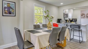 A dining area with a table set for six, a vase with flowers, and a kitchen in the background. - 'The Red Door' Stylish Family Home in Falls Church (Falls Church)