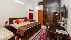 Et soveværelse med seng, skrivebord, garderobeskab, loftventilator og fjernsyn.