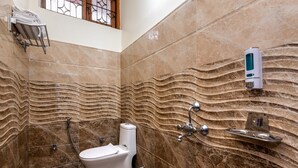Et badeværelse med væg i marmor, toilet, vask og håndklædestang.