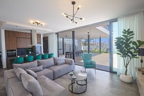 A modern living room with a sofa, coffee table, and a view of the outdoors. - Brand New 4 bedroom villa in Protaras center (Paralimni)