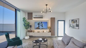 Un salon moderne avec un canapé, un fauteuil vert, une table basse et un téléviseur.