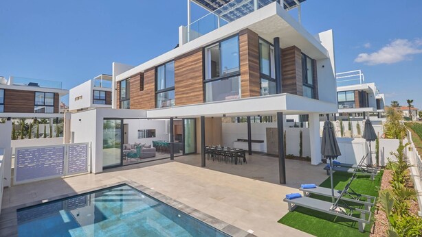 Une maison moderne à deux étages, dotée d’une piscine, d’un espace de détente extérieur et d’un panneau solaire sur le toit.