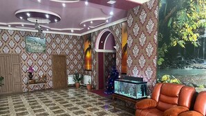 Una habitación con papel tapiz estampado, un acuario grande, un sofá de cuero y un techo decorativo.