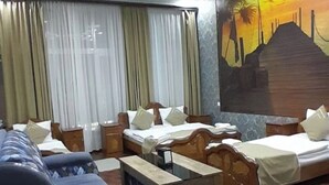 Una habitación de hotel con un sofá, dos camas individuales, un mural y un suelo estampado.