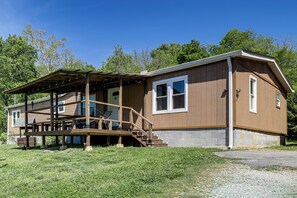 A two-story house with a covered porch, a front door, and a visible staircase. - Furnished Deck, Private Yard! Quaint Knoxville Gem (Knoxville)