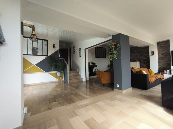 Un vaste espace de vie agrémenté d’un escalier, de parquet et d’un mélange de décorations modernes et classiques.