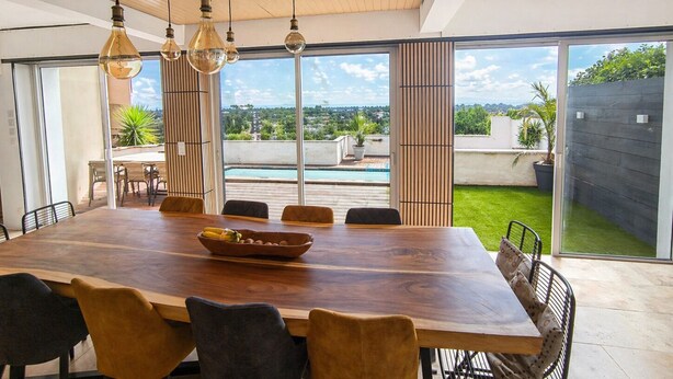 A modern dining area with a large wooden table, multiple chairs, and hanging pendant lights. - Villa Ventoux - 100% Private - 2 steps from Avignon (Villeneuve-lès-Avignon)