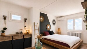 A modern bedroom with a wooden bed, a bedside table with a vase, a ladder, and a wall-mounted mirror. - Villa Ventoux - 100% Private - 2 steps from Avignon (Villeneuve-lès-Avignon)