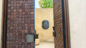 Una entrada protegida con un muro de ladrillo y un letrero que dice 'Asteria Fajjar Villa'.