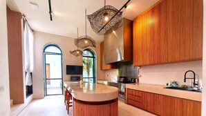 Una cocina moderna con una isla central, muebles de madera e iluminación colgante.