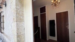 Un pasillo con pared de piedra, un candelabro y una puerta.