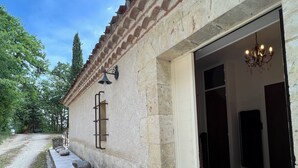 Un edificio de piedra con entrada de tejas, una campana y un candelabro.